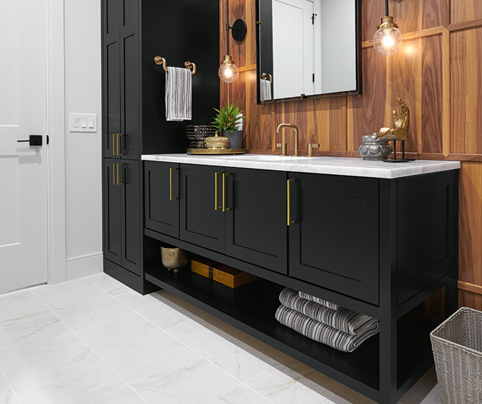 Black matte bath vanity with gold hardware and wood accent wall