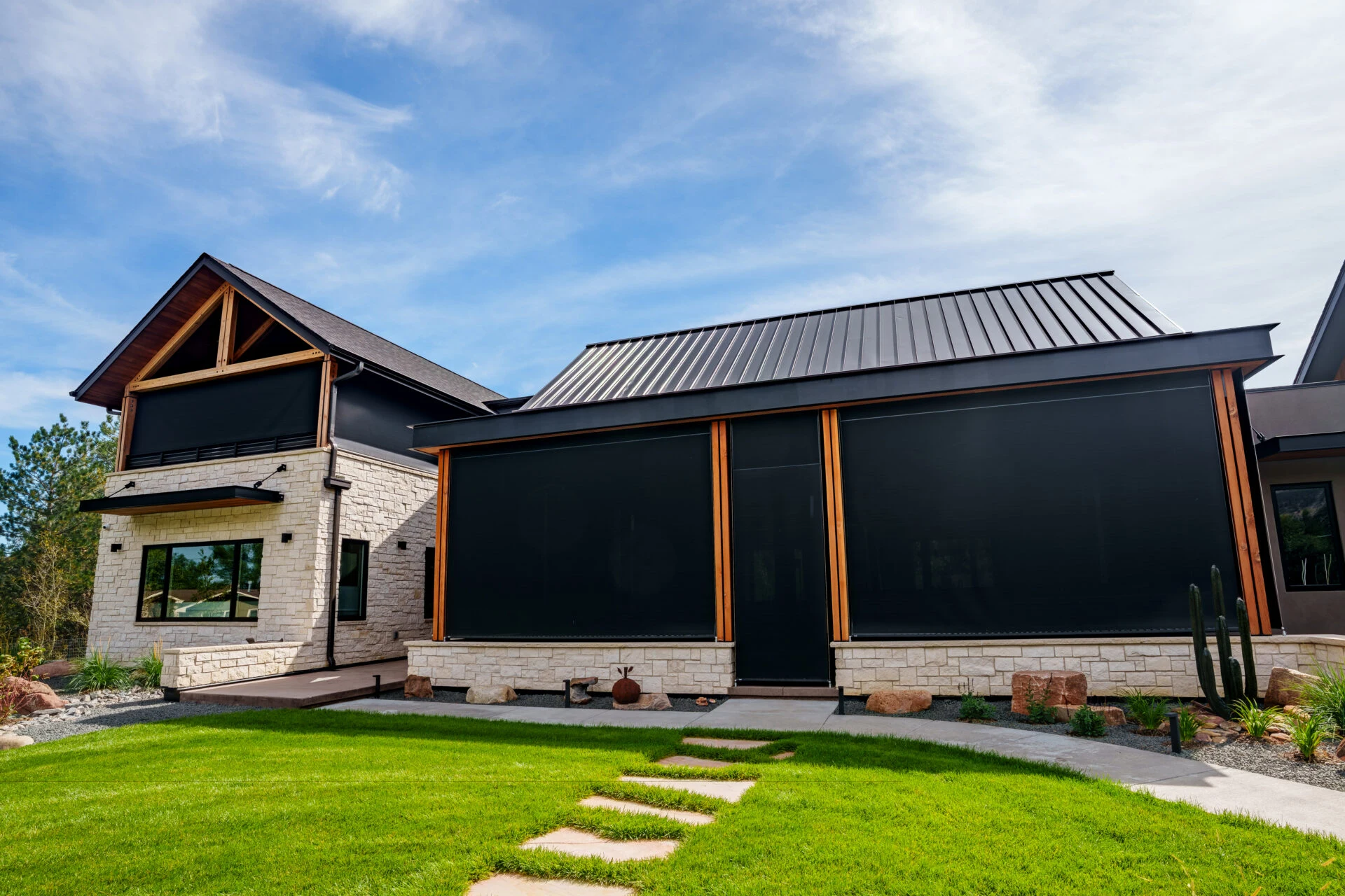Insolroll outdoor solar shades covering the patio and upper balcony of a stone home